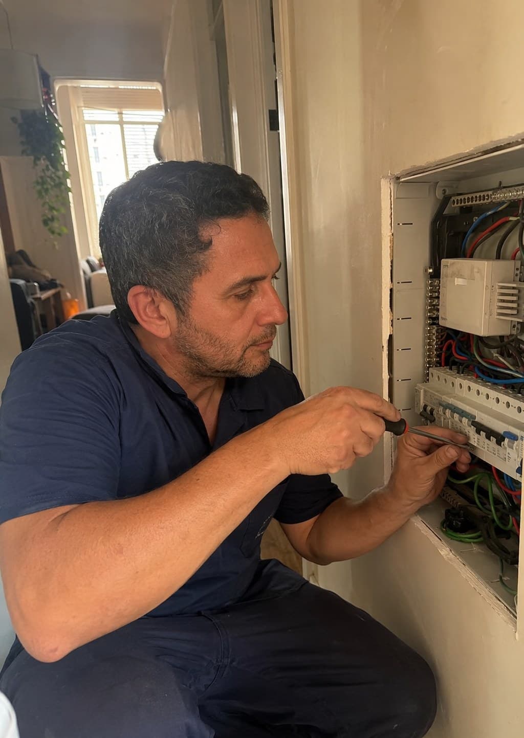 Daniel, eletricista da JD, trabalhando em um quadro de distribuição em apartamento