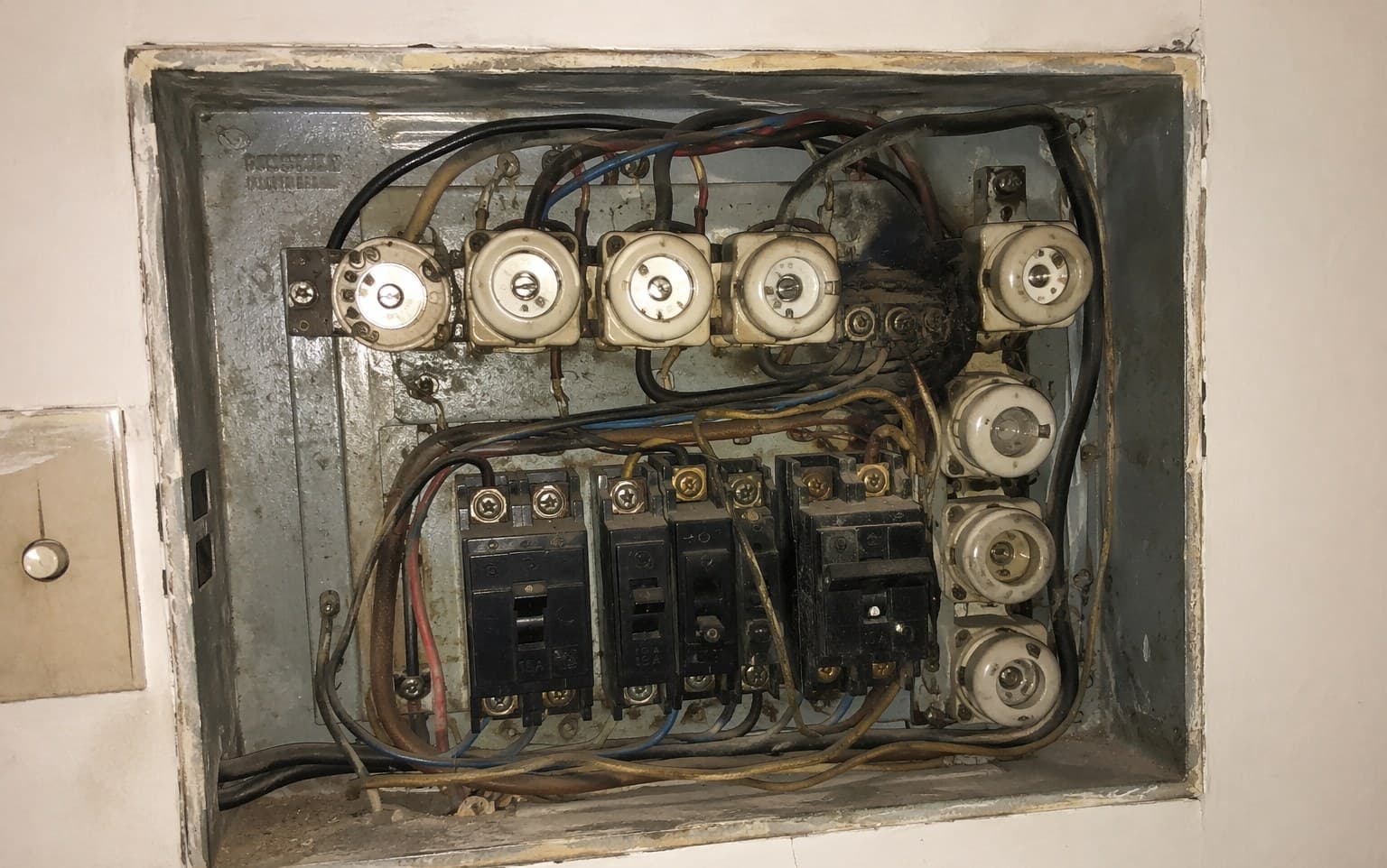 Quadro elétrico antigo antes da reforma, com fiação embolada e fusíveis antigos